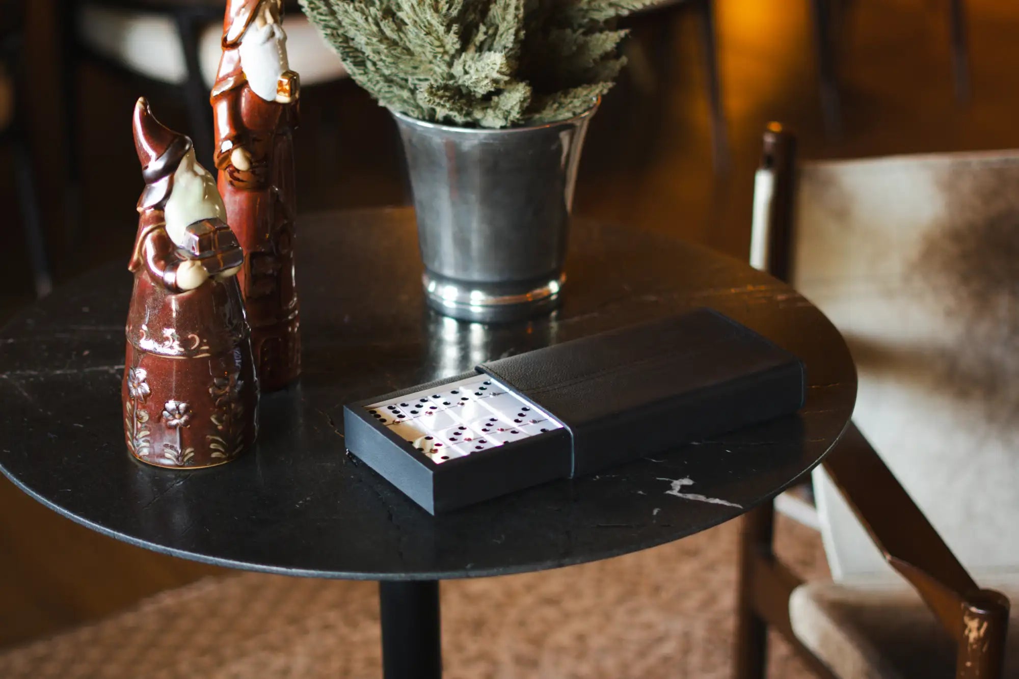 Caja rectangular negra con dominós plateados en el interior, probablemente de una marca de lujo.