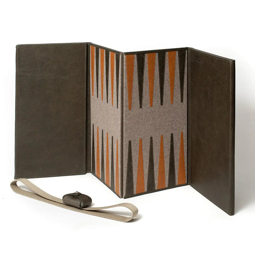 Juego de backgammon con respaldo de cuero marrón y tablero de fieltro gris, con marcas triangulares naranjas y negras, acompañado de una correa a juego color beige.