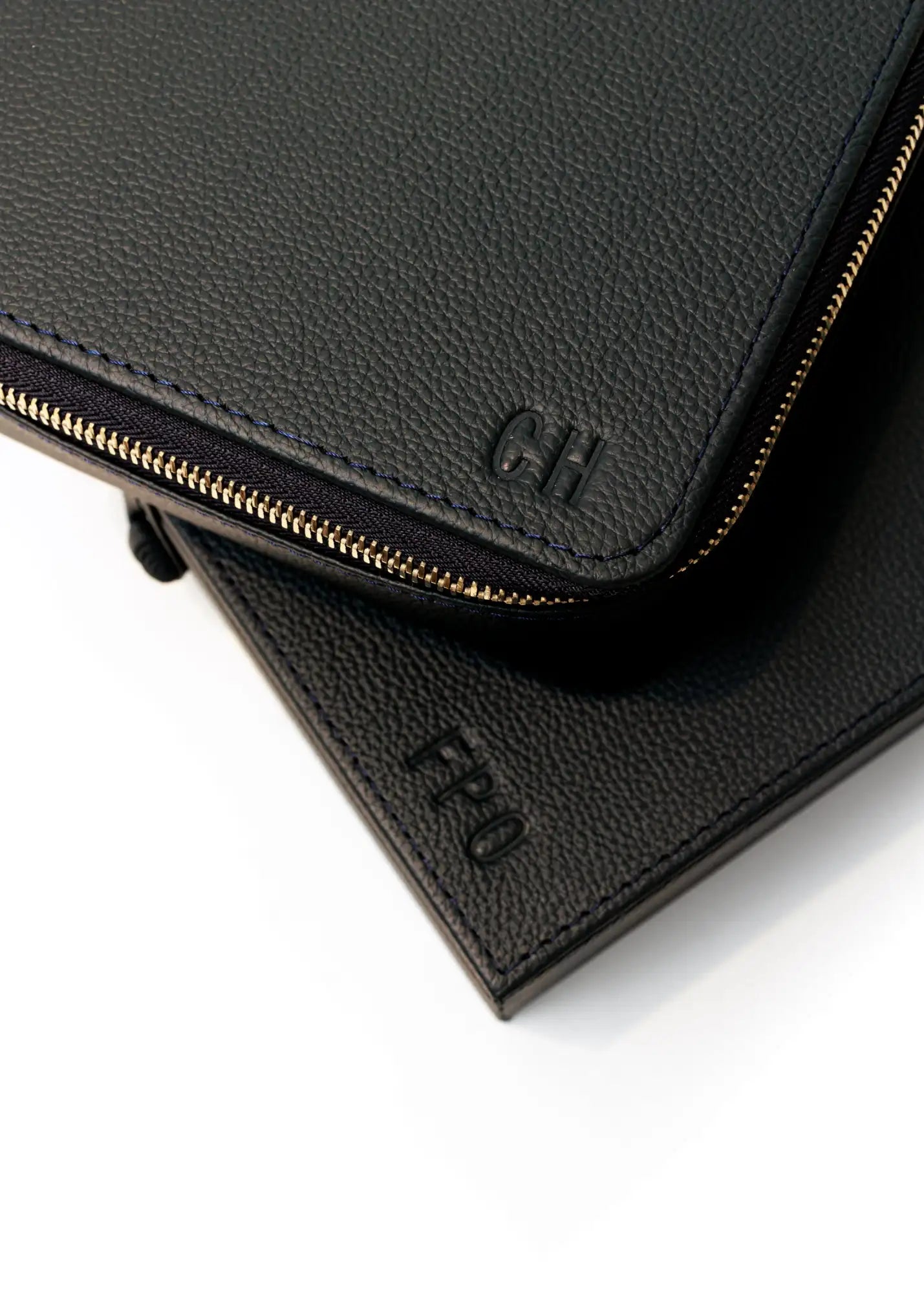 Cartera de cuero negro con cremallera, cremallera en tono dorado e iniciales en relieve.