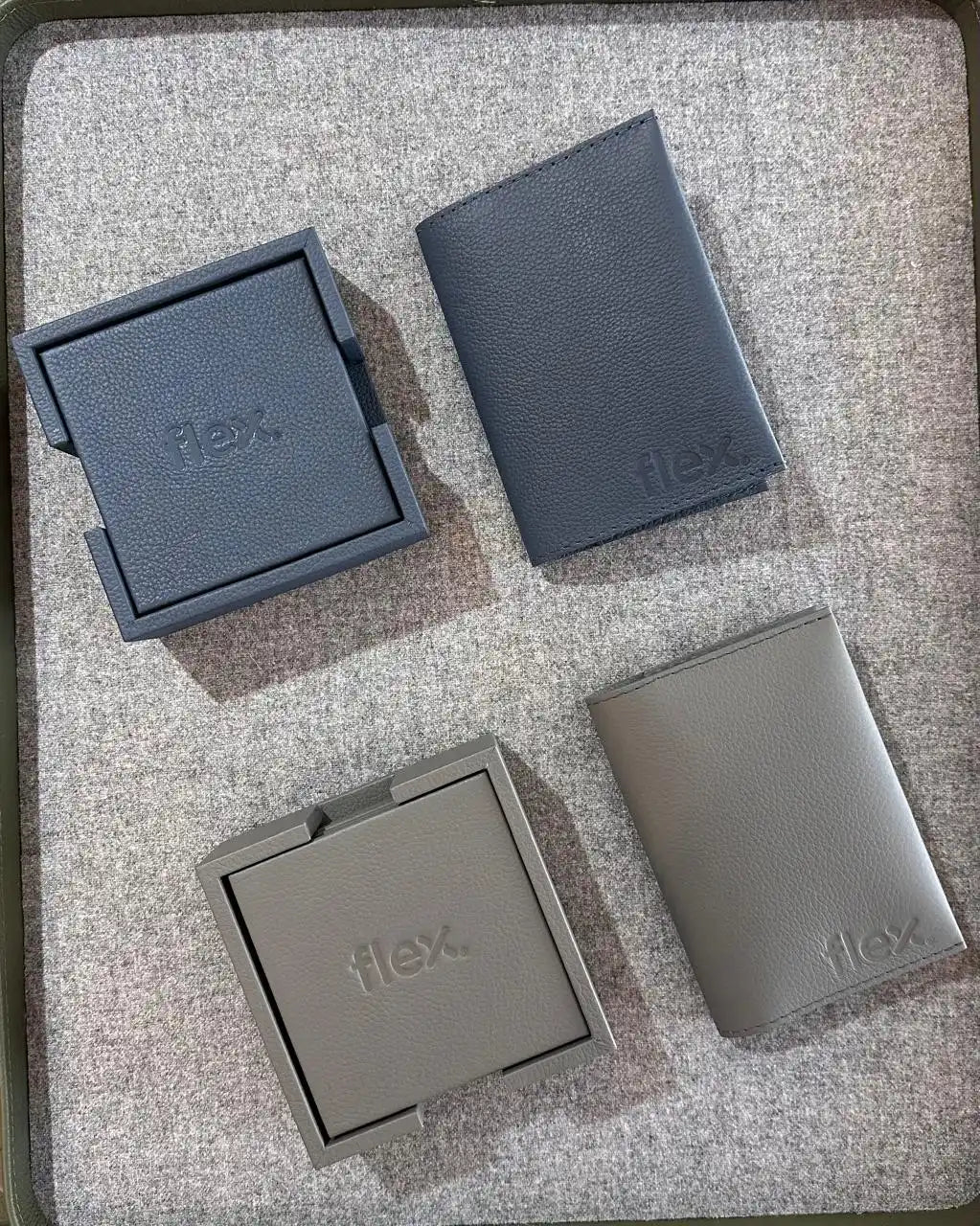 Dos juegos de posavasos de cuero cuadrados y portatarjetas de crédito rectangulares, uno en gris oscuro y otro en gris claro.