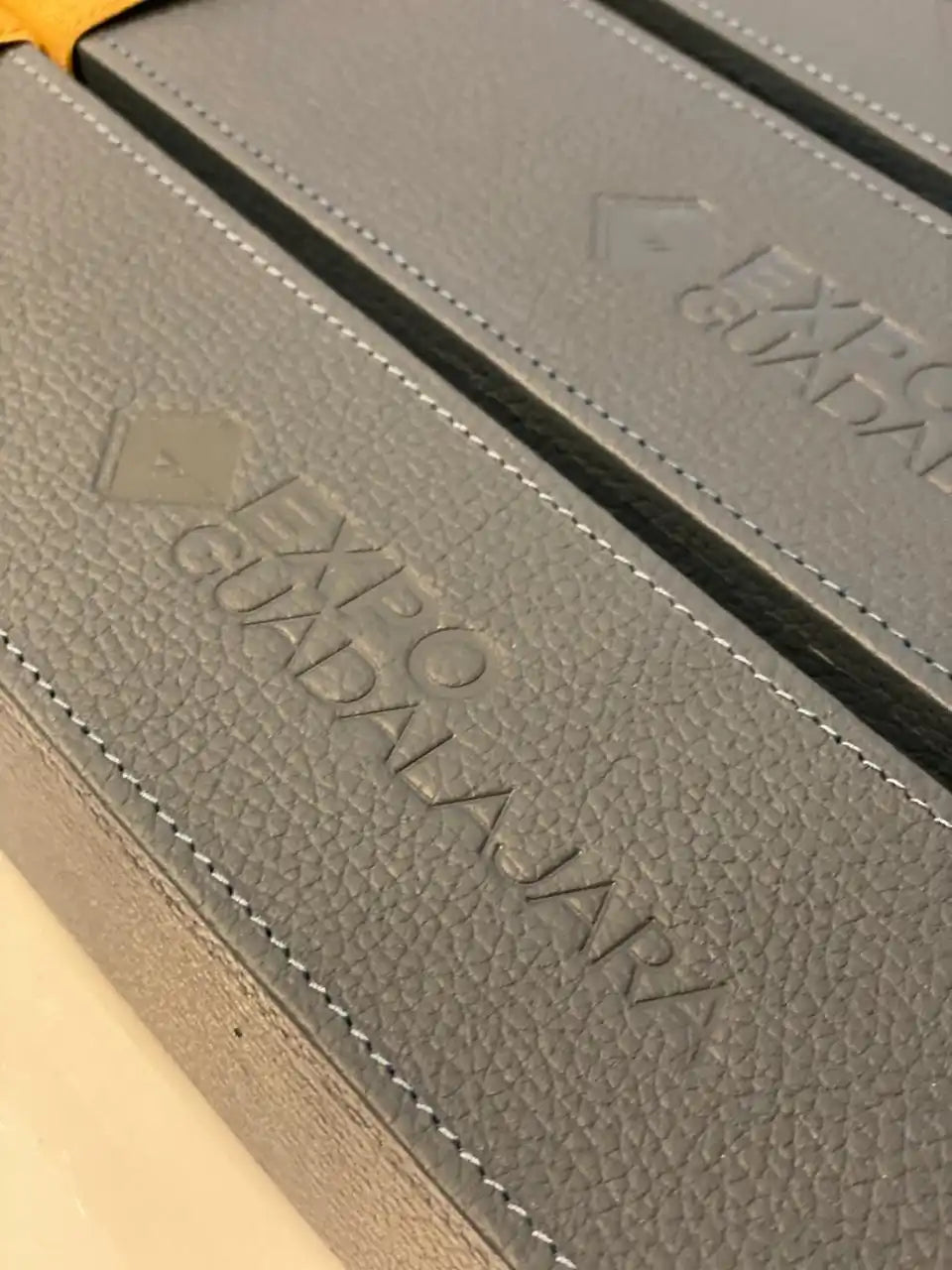 Cajas de cuero sintético gris con costuras blancas.