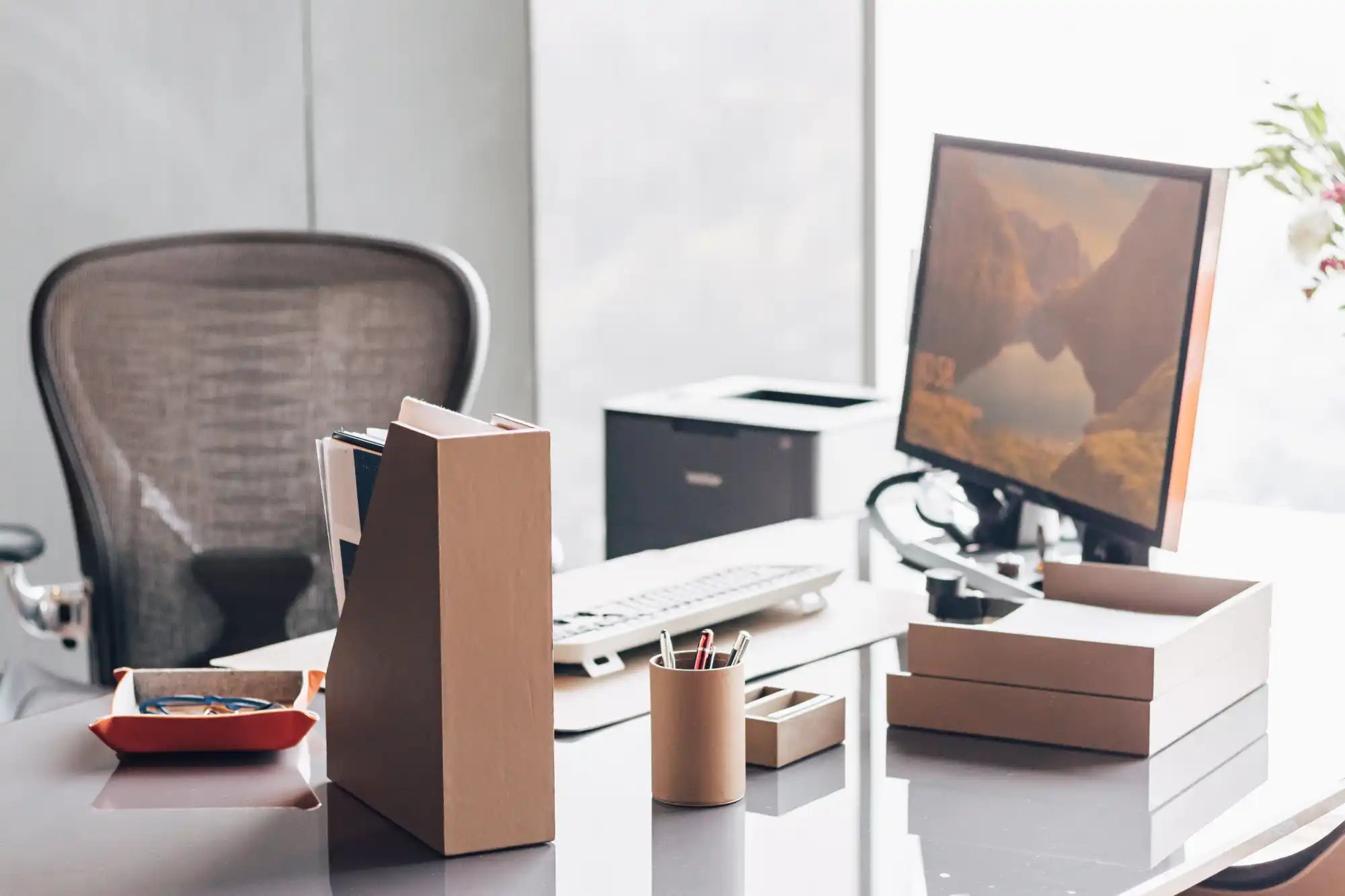 Configuración moderna de escritorio de oficina con un monitor de computadora, silla de oficina y accesorios de escritorio organizados.