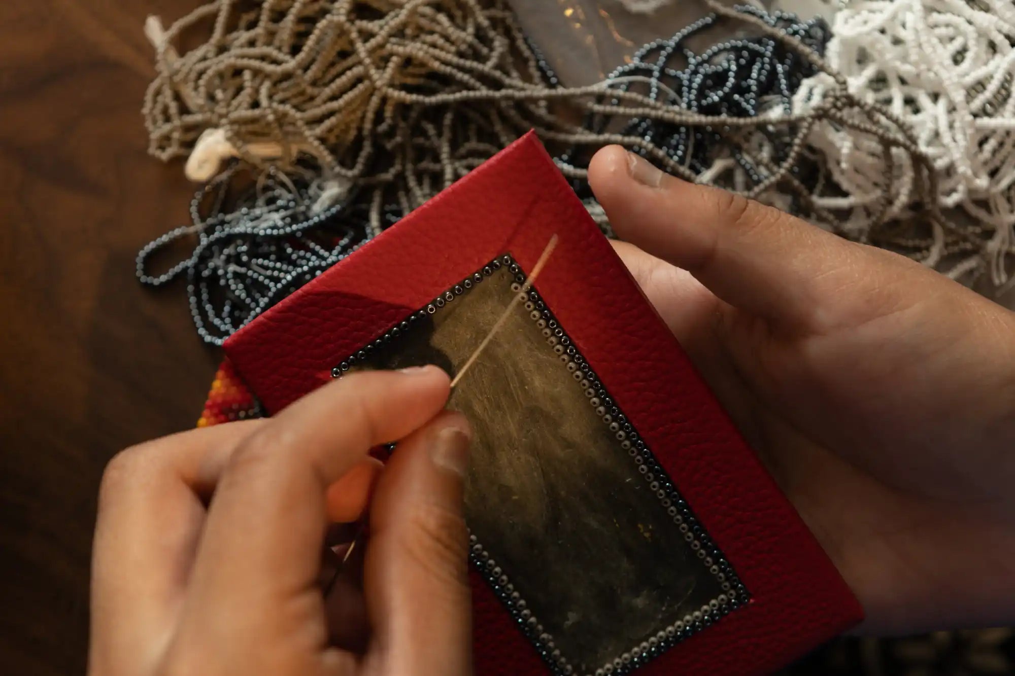Cartera o bolso rojo con un panel de acento metálico siendo sostenido abierto por manos.