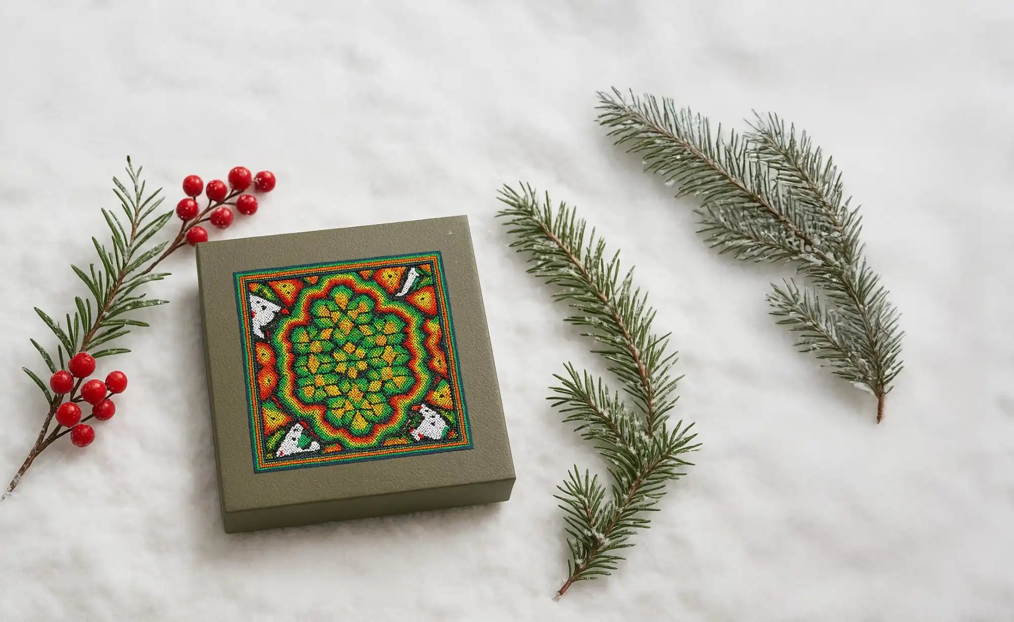 Caja con diseño de mandala verde con bayas rojas y ramas de pino.